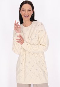 Strickpullover in Creme mit Rautenmuster, weiten Ärmeln und geripptem Saum. Weicher Textur mit lockerer Passform, ideal zum Schichten.
