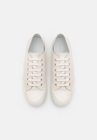 Vita lädersneakers har en slät yta, sex par ögla, och en förstärkt tåhuvud. Fodret är ljusblått.