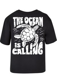 Black cotton t-shirt featuring a large white graphic of a turtle and the phrase "THE OCEAN is CALLING" in bold, playful font.
