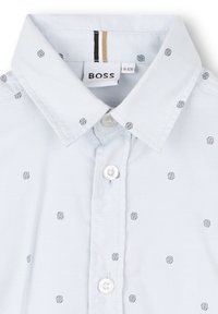 Camicia azzurra a maniche corte con colletto button-down, piccolo motivo a logo ripetuto e chiusura con bottone bianco.