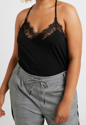 Person wearing a black lace-trimmed camisole and high-waisted gray plaid pants with a drawstring tie, shown from shoulders to thighs.