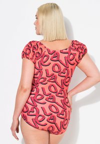 Enbitar swimsuit i korall med svart "love"-text, med korta puffärmar, rund hals bak och ett mjukt, stretchigt tyg.