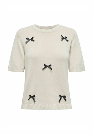 Cream knit sweater with short sleeves, featuring black ribbon bows decoratively placed across the front and ribbed edges at the neckline and sleeves.