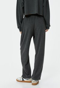 Grijze, getextureerde wijde broek met een elastische tailleband. Draag het met witte sneakers met zwarte accenten en een cropped donker top.
