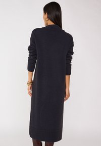 Cardigan lungo, di un blu navy scuro, lavorato a maglia, con colletto sciallato, polsini e orlo a coste. Texture morbida, silhouette dritta e senza chiusure visibili.