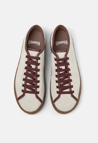 Pair of beige suede sneakers with brown laces, trim, and rubber soles, viewed from above, branded with "CAMPER" inside.