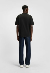 Czarna bawełniana koszulka z krótkim rękawem, prosty krój. W połączeniu z ciemnoniebieskimi dżinsami z delikatnym rozszerzeniem, noszona z białymi butami.