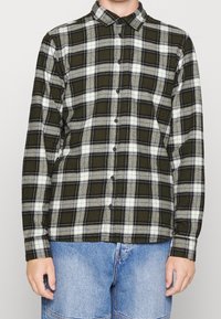 Zeleno-šedá kostičkovaná flanelová košile s knoflíkovým zapínáním vpředu, dlouhými rukávy a límcem. Měkká textura s kontrastními bílými pruhy.