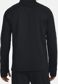 Schwarze, langärmlige Jacke mit Reißverschlusskragen, die eine glatte Struktur und ein minimalistisches Design aufweist, von hinten gezeigt.