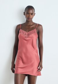 Satin nattkjole i dusty rose farge med justerbare spagettistropper, blonder på utringningen og en glatt, lett tekstur.