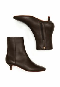 Bottines en cuir marron avec un bout pointu, un petit talon kitten bas et une fermeture éclair latérale en accent. Texture lisse avec un design élégant.