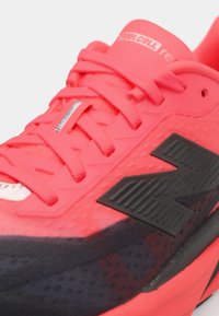 Baskets de sport rouges et noires avec une tige en maille texturée, un col rembourré et un logo proéminent avec de saisissants détails noirs.