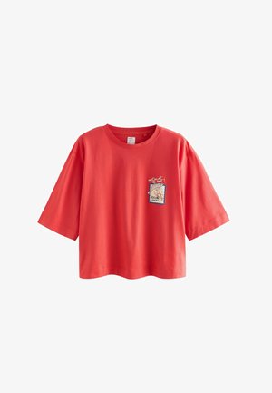 Rotes Baumwoll-T-Shirt mit kurzen Ärmeln, das auf der linken Seite ein aufgenähtes Design in Form einer Briefmarke zeigt.