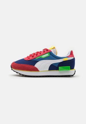 Lavtop sneaker med blå, røde, hvide, gule og grønne paneler, røde snørebånd, Puma-logo på siden og sort gummisål.