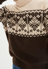 Maglione a maglia marrone e beige con collo alto a coste. Presenta un motivo geometrico in marrone scuro, inclusi motivi a fiocco di neve. Texture morbida.