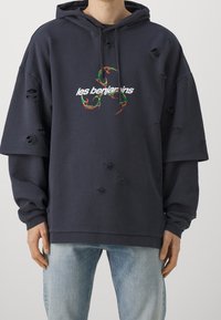 Felpa oversize color navy con dettagli vissuti, caratterizzata da un testo grafico colorato "les benjamins" sul davanti e una morbida texture in cotone.