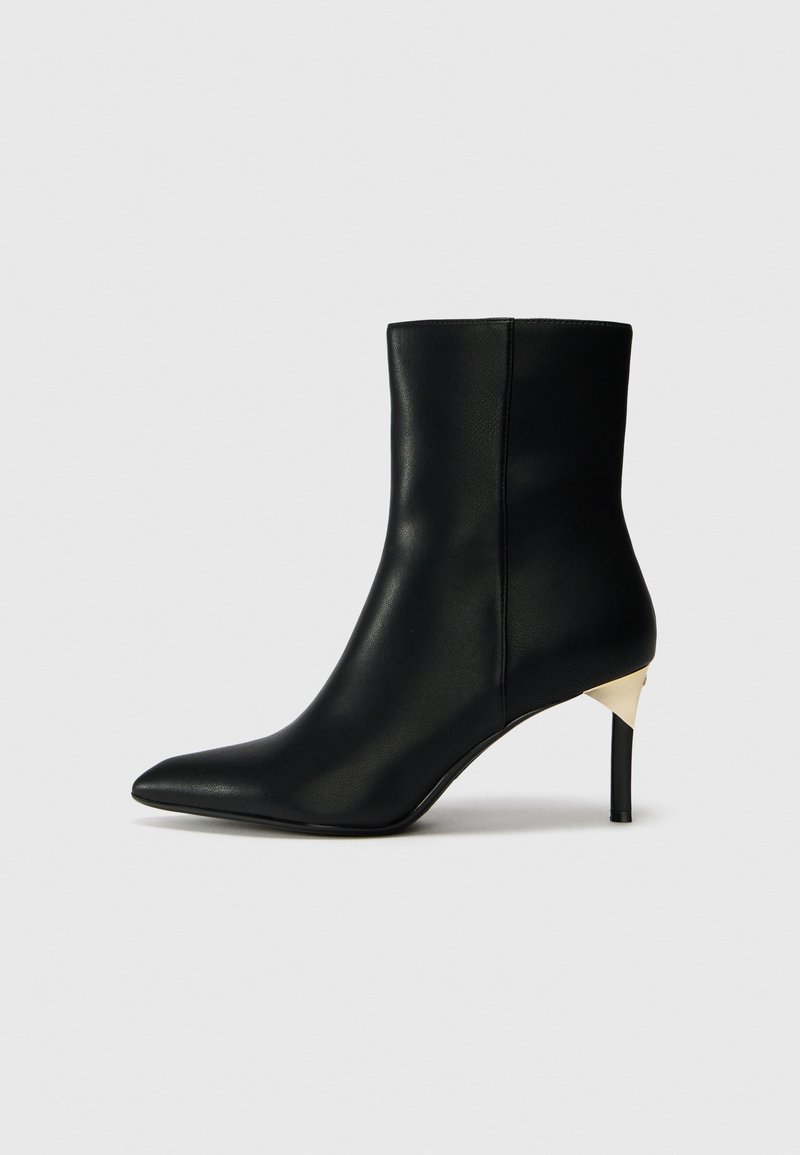 Stivale alla caviglia in pelle nera con punta appuntita e tacco accentato in oro contrastante. Texture liscia, design elegante e silhouette aderente.