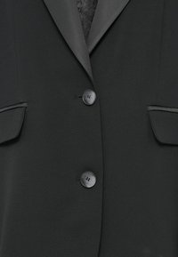 Zwarte blazer met een gladde stof, een notch lapel, twee voorzakken en drie ronde knopen met een matte afwerking.