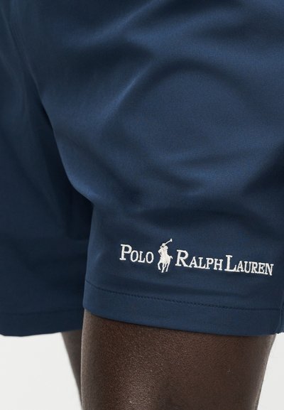 Σκούρο μπλε σορτς με το λογότυπο Polo Ralph Lauren κεντημένο πάνω από το γόνατο σε ένα άτομο με σκούρο δέρμα.