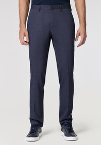 Pantaloni da abito blu navy in tessuto textured, a gamba dritta e con fronte piatta. Abbinati a sneaker scure e a una camicia blu navy aderente.