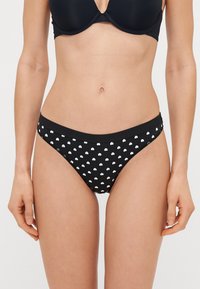 Mustmust põhja valge südame mustriga, valmistatud pehmest kangast, madala vöökohtaga ja elastse vöörihmaga mugavuse tagamiseks.