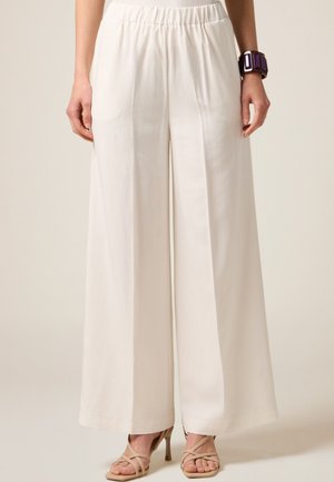 Pantaloni a gamba larga color crema con elastico in vita. Tessuto morbido, leggero e dotati di due tasche laterali.