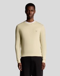 Ανοιχτό κίτρινο πουλόβερ με μακριά μανίκια και στρογγυλή λαιμόκοψη, υφασμένο με υφή και με μικρό λογότυπο στο αριστερό στήθος, συνδυασμένο με μαύρο παντελόνι.