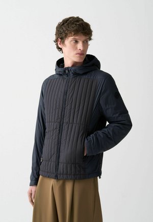 Hooded puffer jacket in dark navy with a quilted pattern on the upper body, featuring a zipper closure and side pockets. Smooth fabric texture.