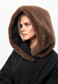 Sort overtøj med en stor brun pelsforet hætte. Hætten har en blød tekstur, og jakken har en knaplukning og et slankt design.