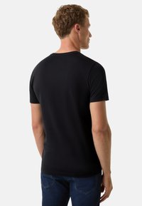 Černé tričko s krátkým rukávem vyrobené z bavlny, s kulatým výstřihem a hladkým povrchem. Tričko je na sobě, zobrazuje zadní pohled.