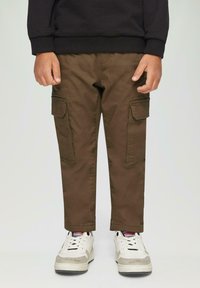 Cargo broek in donkergroene katoen met zijzakken, gecombineerd met witte sneakers met grijze accenten en gestructureerde zolen.