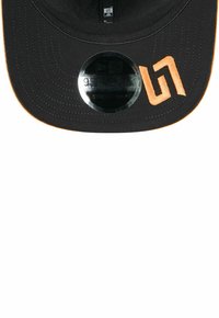 Czarna czapka baseballowa z pomarańczowym haftowanym logo i akcentującymi przeszyciami. Posiada zapięcie na zatrzask oraz płaską daszek. Teksturowana tkanina.