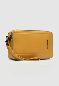 Portafoglio in pelle gialla con chiusura a cerniera, dettagli della cerniera blu, cinturino da polso staccabile e forma rettangolare elegante.