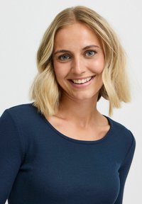 Námorníckomodrý rebrovaný top s dlhým rukávom a okrúhlym výstrihom. Textília má hladkú štruktúru, tesne priliehajúcu k telu bez viditeľných vzorov.