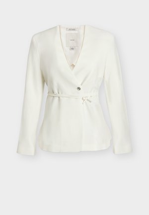 Blazer blanc à manches longues avec col en V, fermeture par un seul bouton et ceinture fine nouée à la taille, présenté sur un fond uni.