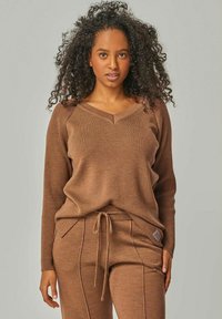 Brauner gerippter Pullover mit V-Ausschnitt und langen Ärmeln, kombiniert mit passenden Hosen mit Kordelzugbund und Verzierungsdetails.