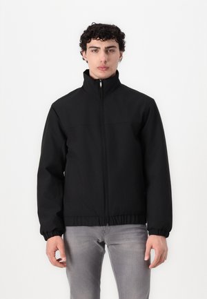 Svart zip-up jakke med ståkrage, elastiske mansjetter og midjebånd. Glatt, teksturert stoff; minimal design, uten synlige mønstre eller detaljer.