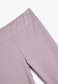 Leggings di un leggero colore lavanda realizzati in un tessuto liscio ed elastico. Presentano una ampia vita elastica e un design minimalista senza motivi visibili.