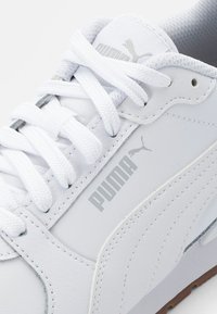 Weiße Leder-Sneaker mit auffälligem grauen PUMA-Logo, strukturierten Schnürsenkeln und einer Gummisohle. Besitzt eine glatte Oberfläche und verstärkte Nähte.