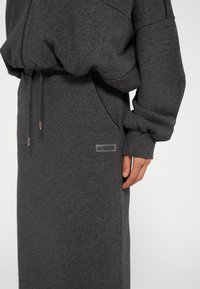 Grauer glitzernder Pullover mit lockerer Passform. Verfügt über einen Tunnelzug am Bund, Seitentaschen und ein Etikett mit der Aufschrift "10 DAYS". Weicher Stoff.