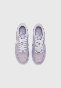 Fialové tenisky Nike s hladkým syntetickým zvrškom so perforáciami, bielymi šnúrokami a strieborným logom na boku.