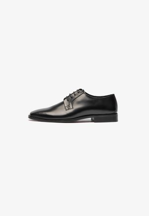 Zapato de vestir de cuero negro con un diseño elegante, punta afilada y cierre de cordones de cinco orificios. Textura suave y costuras mínimas. Suela de goma.