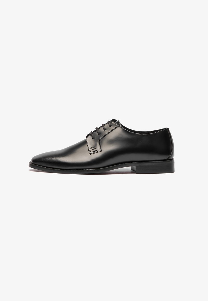 Zapato de vestir de cuero negro con un diseño elegante, punta afilada y cierre de cordones de cinco orificios. Textura suave y costuras mínimas. Suela de goma.