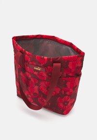 Sac fourre-tout floral rouge avec une surface texturée, orné de fleurs rouges foncées et d'un logo doré, équipé de poignées en tissu robustes et d'un intérieur spacieux.
