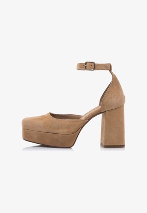 Buty na wysokim obcasie z platformą z zamszu w kolorze jasnobrązowym, z masywnym blokowym obcasem i paskiem wokół kostki zapinanym na metalową klamrę.