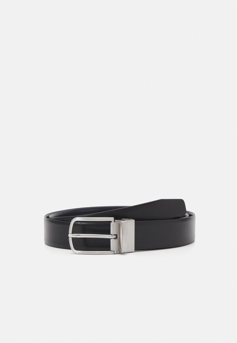 Zwarte leren riem met een rechthoekige zilveren metalen gesp. De riem is glad met scherpe randen en een eenvoudig ontwerp, zonder versieringen.