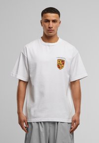 Hvid bomulds t-shirt med rund halsudskæring og korte ærmer. Har et farverigt logo på venstre bryst og en afslappet pasform.