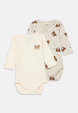 Two long-sleeved baby bodysuits: one cream with a bear print, the other light gray with a repeating bear pattern. Made of soft cotton.