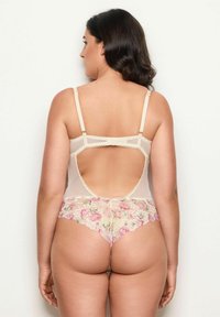 Alusvaatteiden bodysuit, jossa on nude-mesh-yläosa, vaaleanpunaisesta ja kermasta valmistettu kukkakuvioinen alaosa, avara selkädesign, säädettävät hihnat ja koristeellinen nauha.