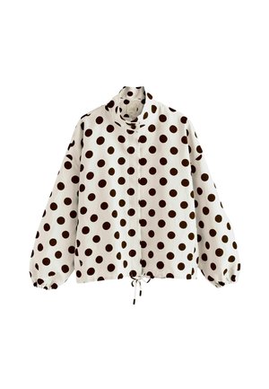 Chaqueta blanca de manga larga con lunares negros, cuello alto, puños elásticos, cierre frontal y cordón en el dobladillo.